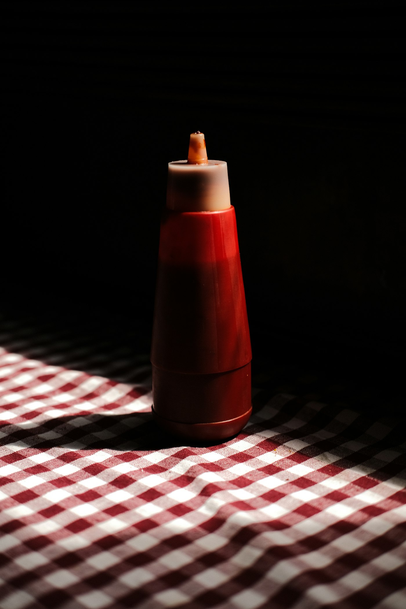 Red hot sauce squeeze bottle on a checkered tablecloth