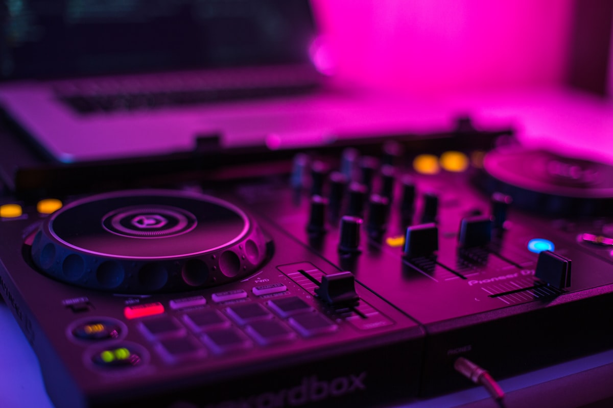 Hands on a DJ controller under neon light